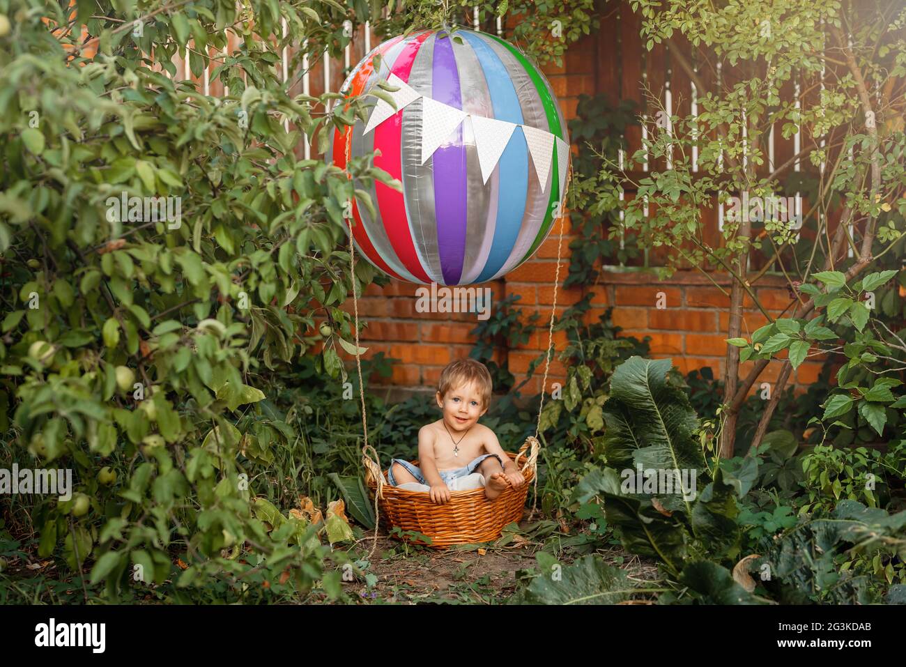 Pretty child riding hot air balloon. Boy having fun flying up. Stock Photo