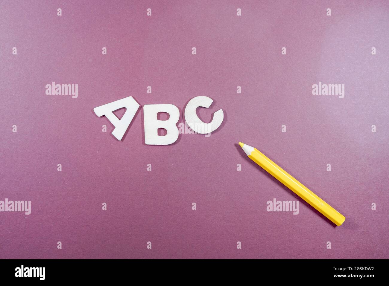 Top view of 'ABC' letters on a purple surface with a yellow pencil Stock Photo