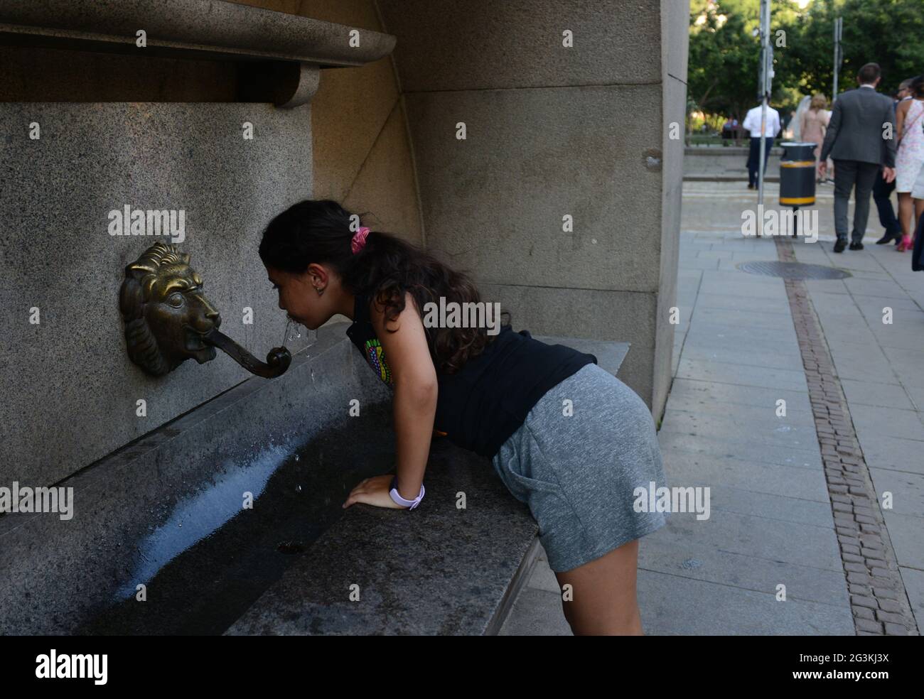 A girl drinking from an Old venetian fountain with a lion head in Sofia, Bulgaria. Stock Photo