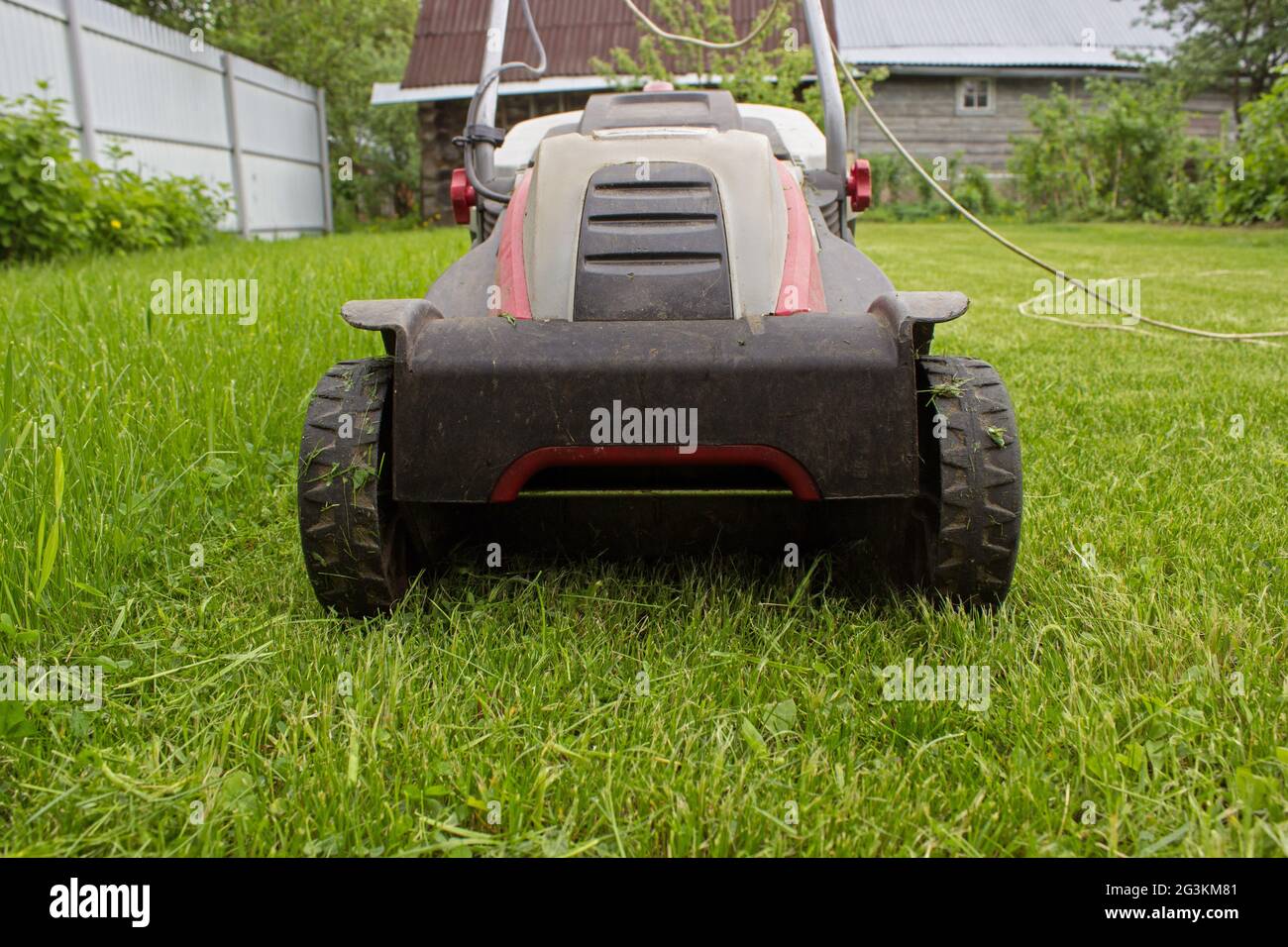 A lawn mower on a lush green. Gardening background. Details of landscaping and gardening Stock Photo