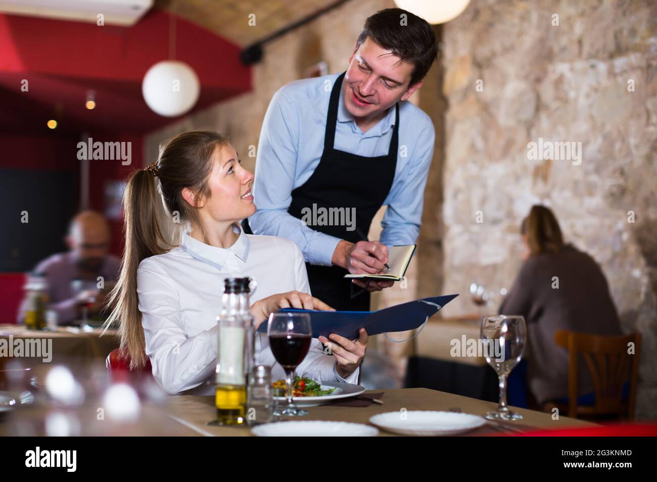 Hospitable waiter helping nice girl with menu Stock Photo Alamy