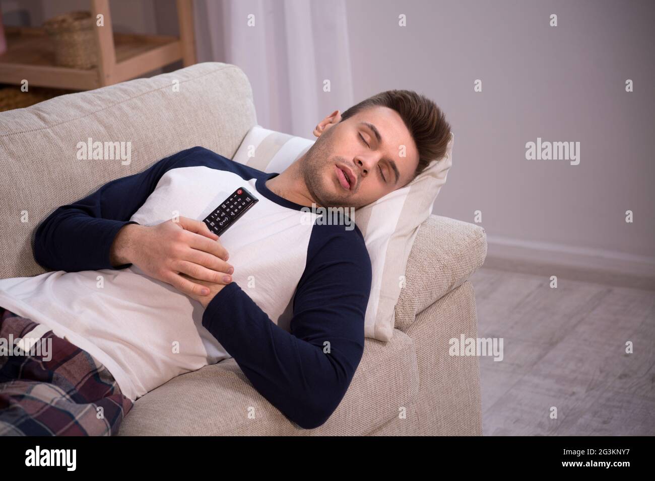 Man sleeping on couch with TV remote in his hands. Stock Photo