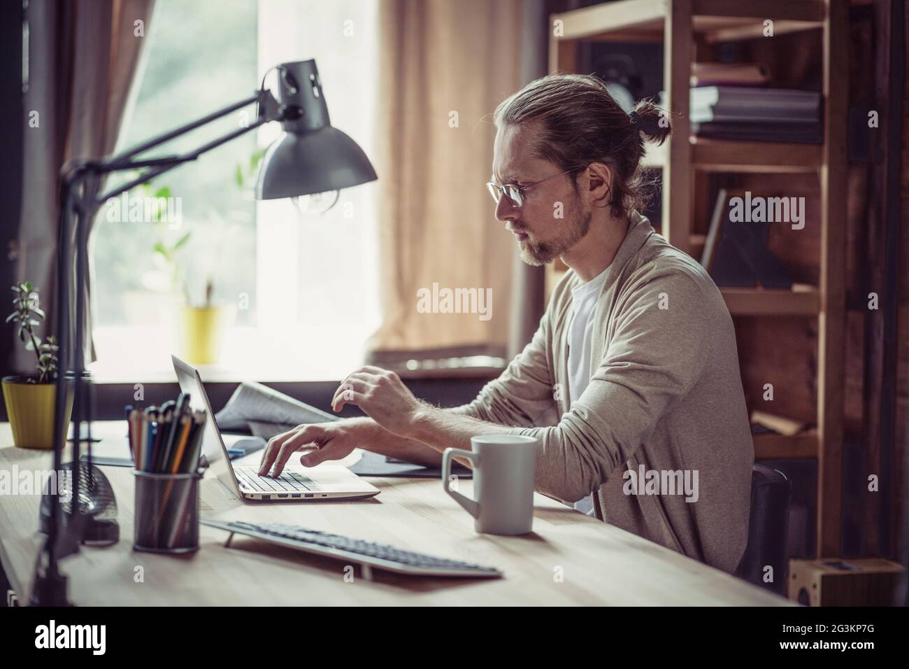 Freelancer sitting at table typling on laptop. Stock Photo