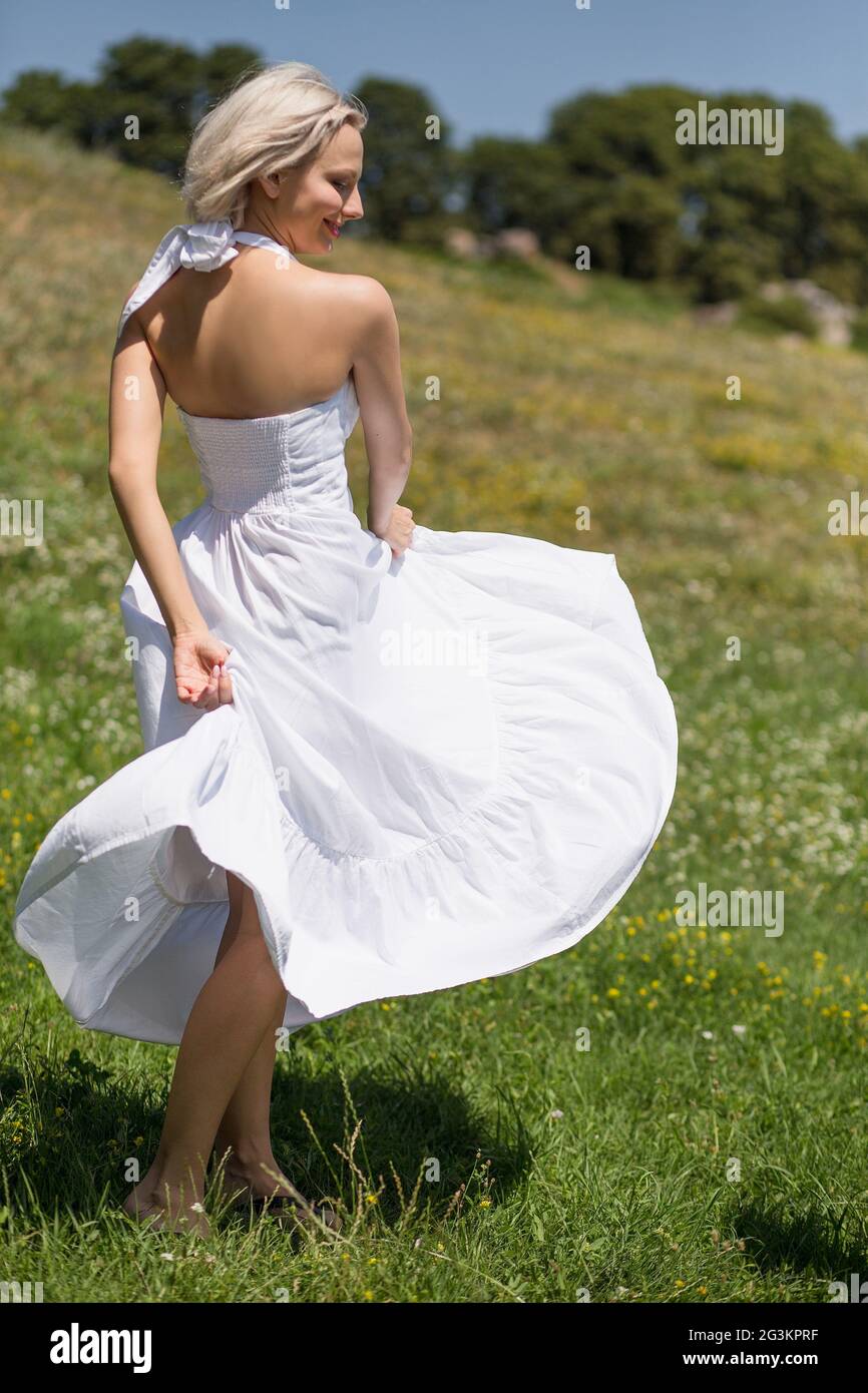 Yong woman in long white dress in a meadow. Stock Photo