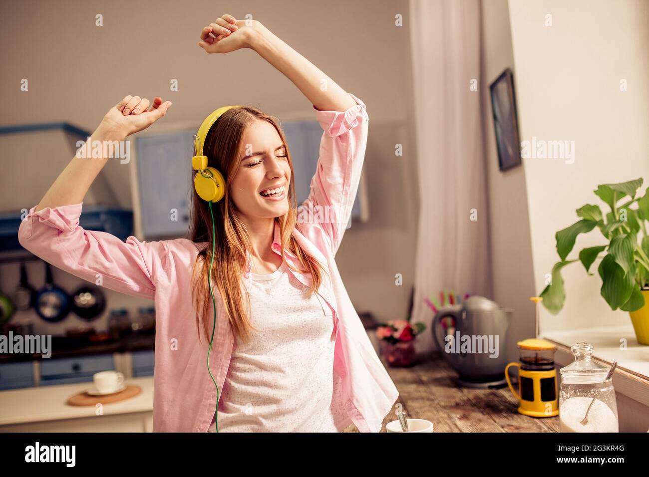 Girl in the kitchen dancing listening music in headphones Stock Photo Alamy