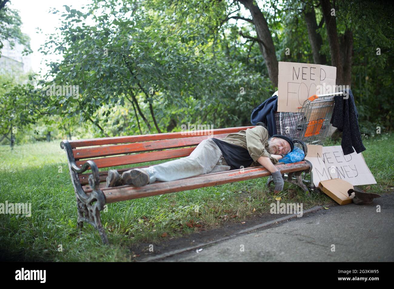 View of homeless old man on the bench in city park. Stock Photo