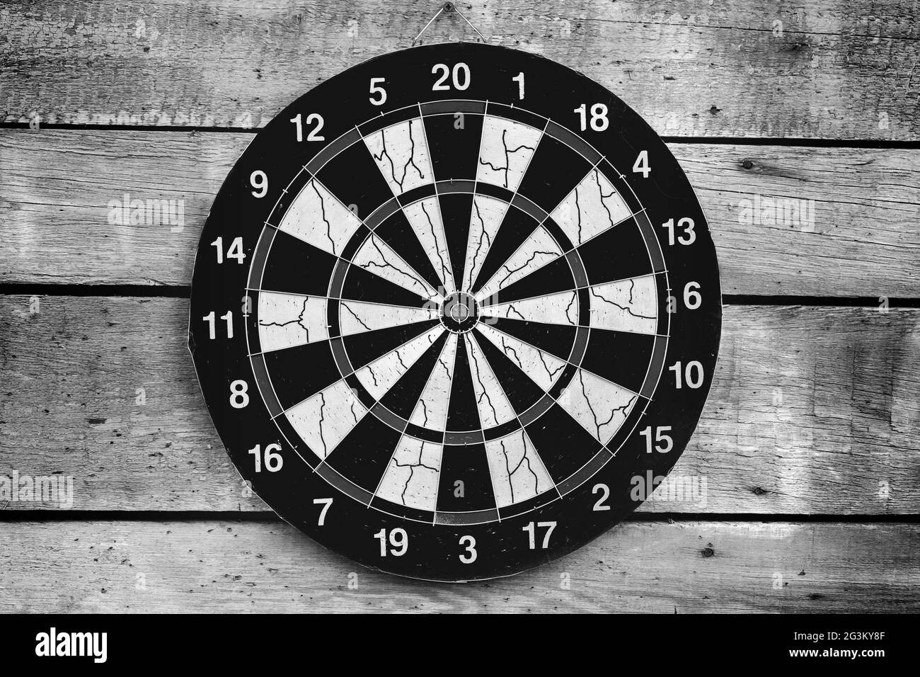 Dartboard mounted on a wooden wall, front view. Black and white photo background Stock Photo