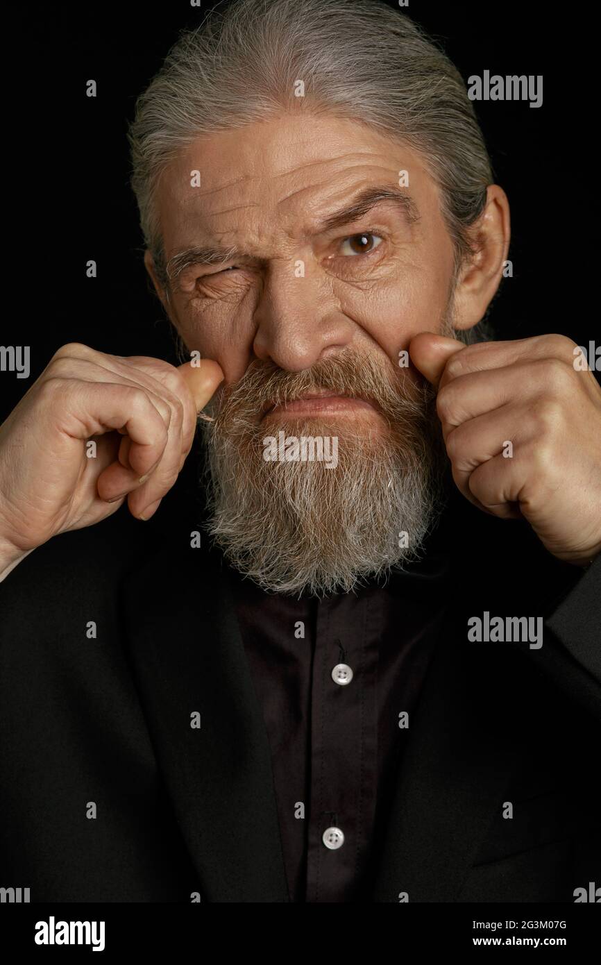 Wrinkled old man holding fists close to face. Stock Photo