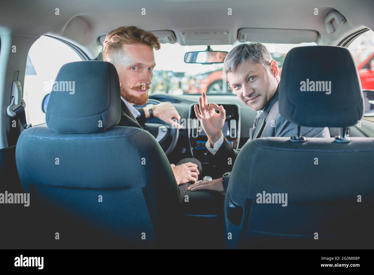 Vehicle dealer and buyer sitting on front seats in new car. Stock Photo