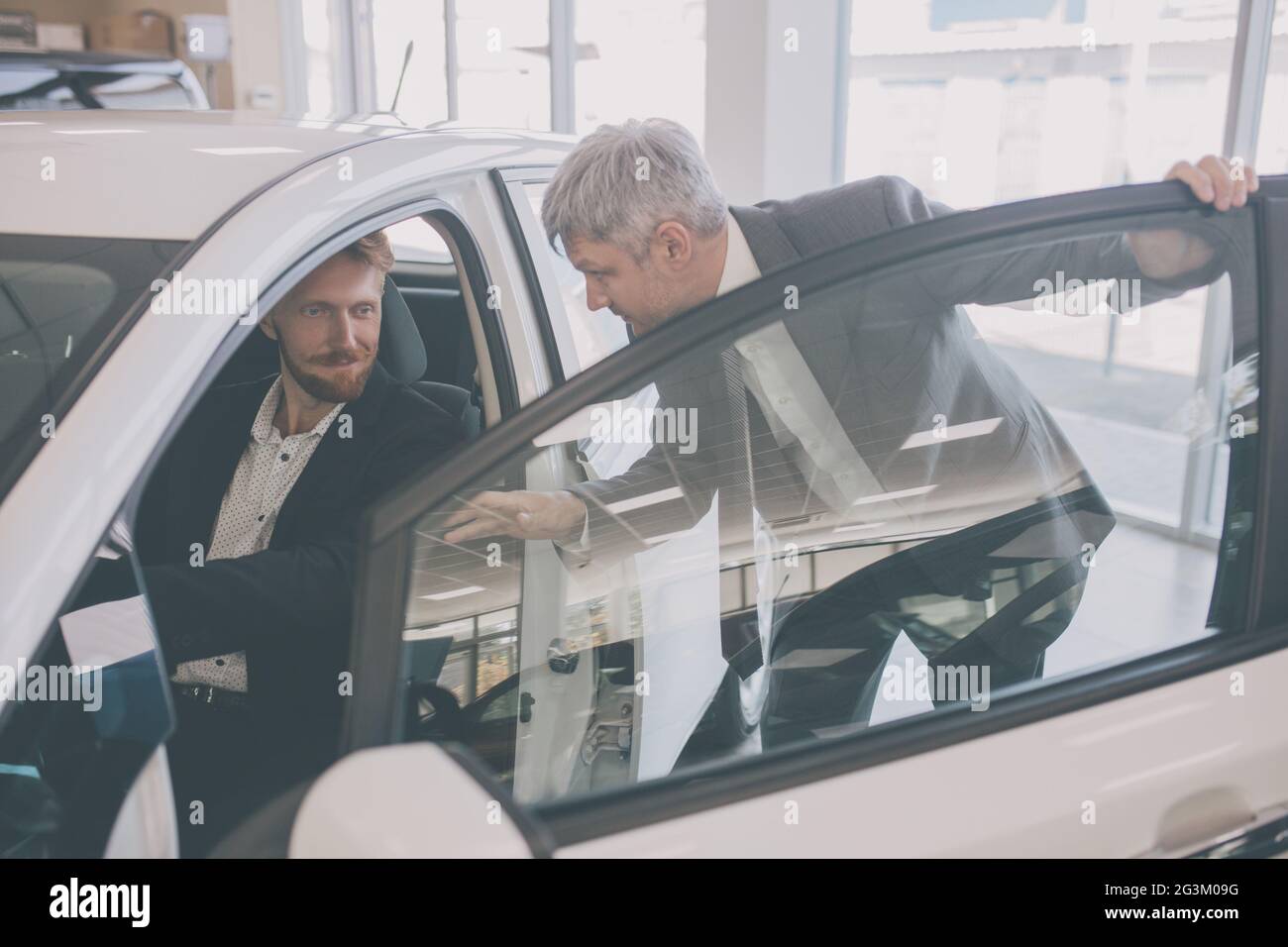 Vehicle dealer showing new car to young handsome man. Stock Photo