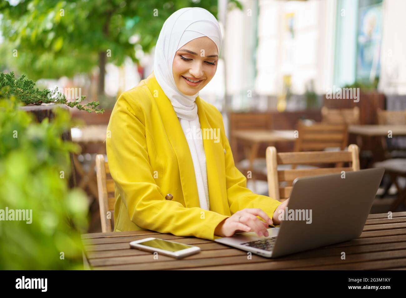 Beautiful smiling muslim woman with laptop at cafe Stock Photo - Alamy