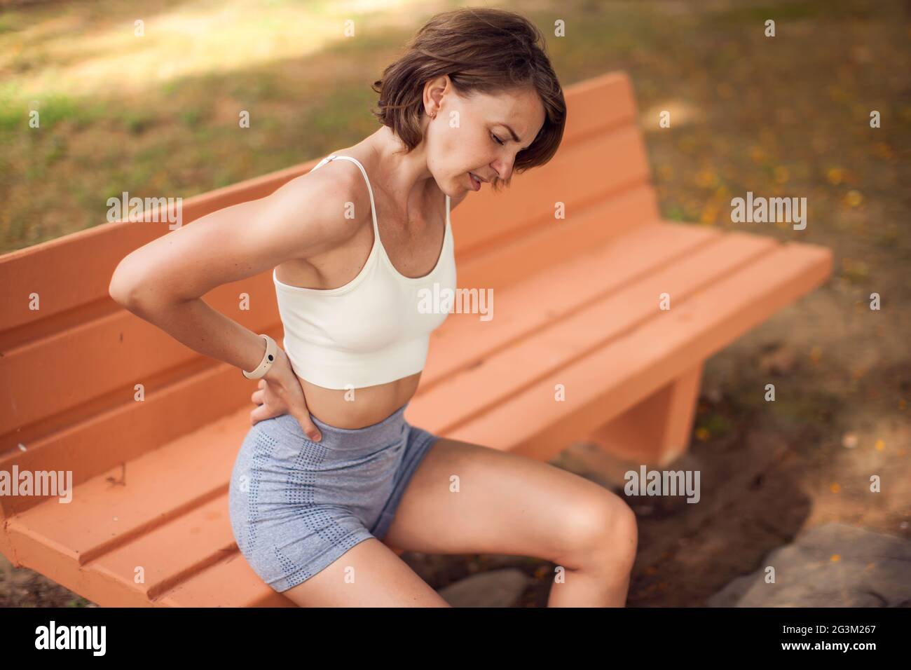 Woman with back pain in the park. Fitness, healthcare and medicine concept Stock Photo