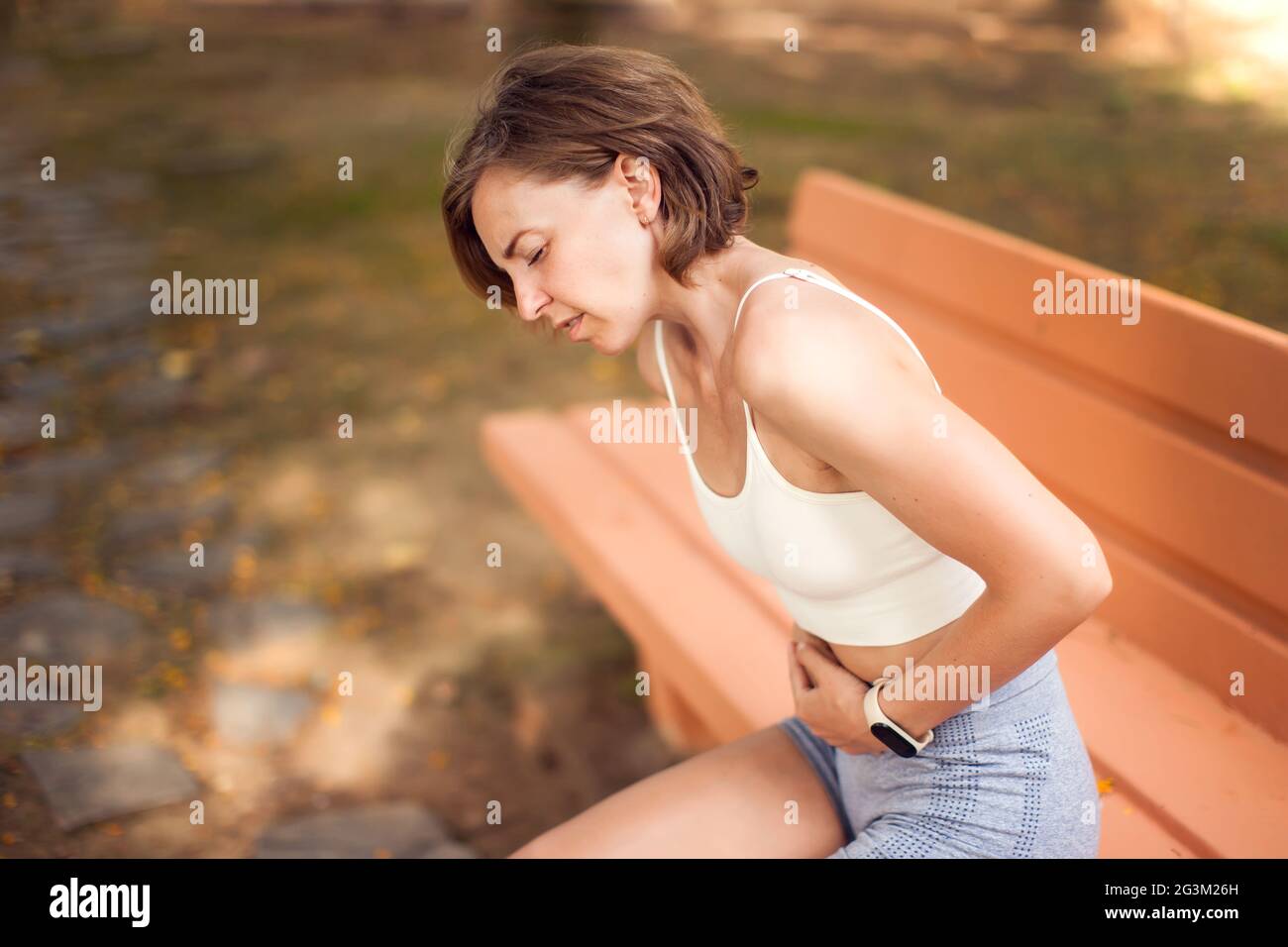 Sports woman with stomach pain in the park. Fitness, healthcare and medicine concept Stock Photo