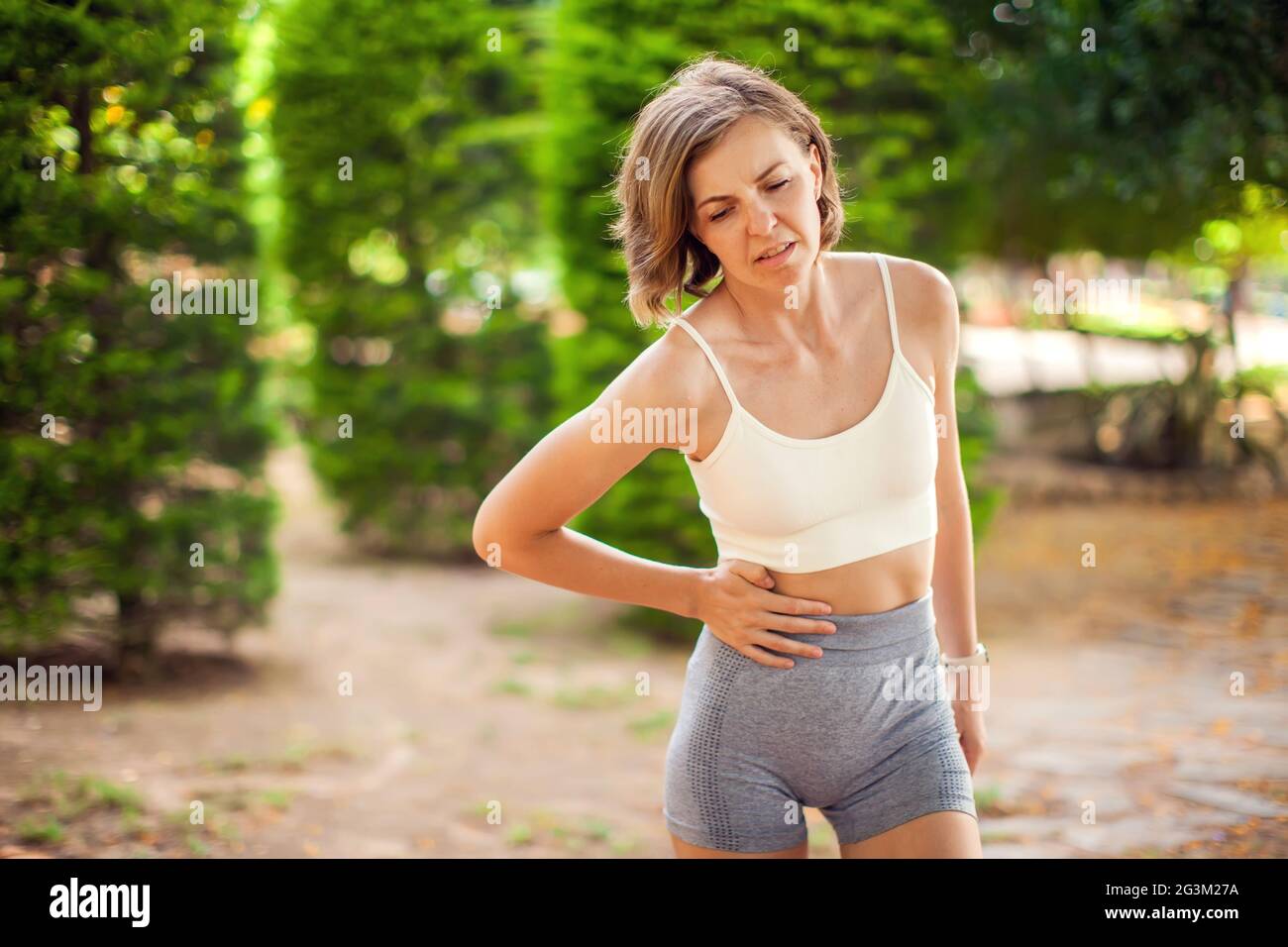 Sports woman with stomach pain in the park. Fitness, healthcare and medicine concept Stock Photo