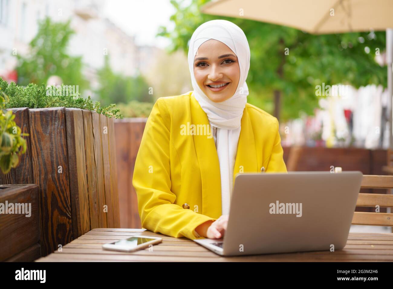 Beautiful smiling muslim woman with laptop at cafe Stock Photo - Alamy