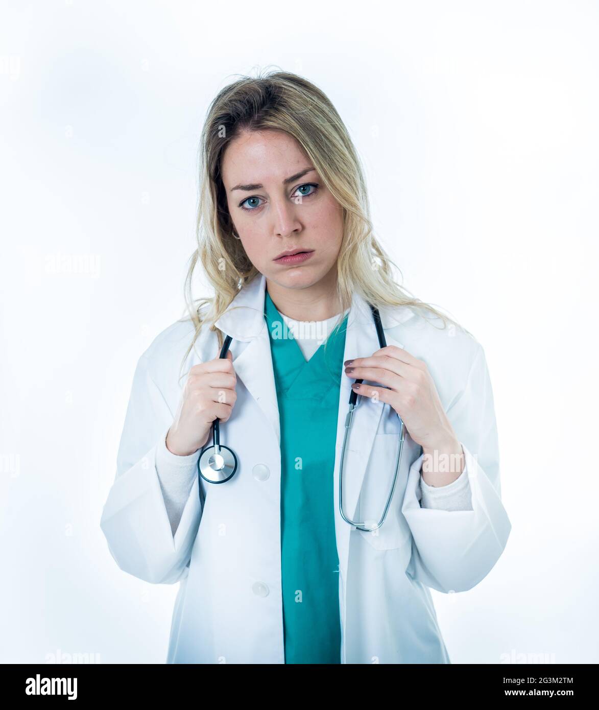 Overwhelmed female doctor or nurse wearing white coat over green scrub hospital uniform. frustrated and tired working at intensive care unit. Emotiona Stock Photo