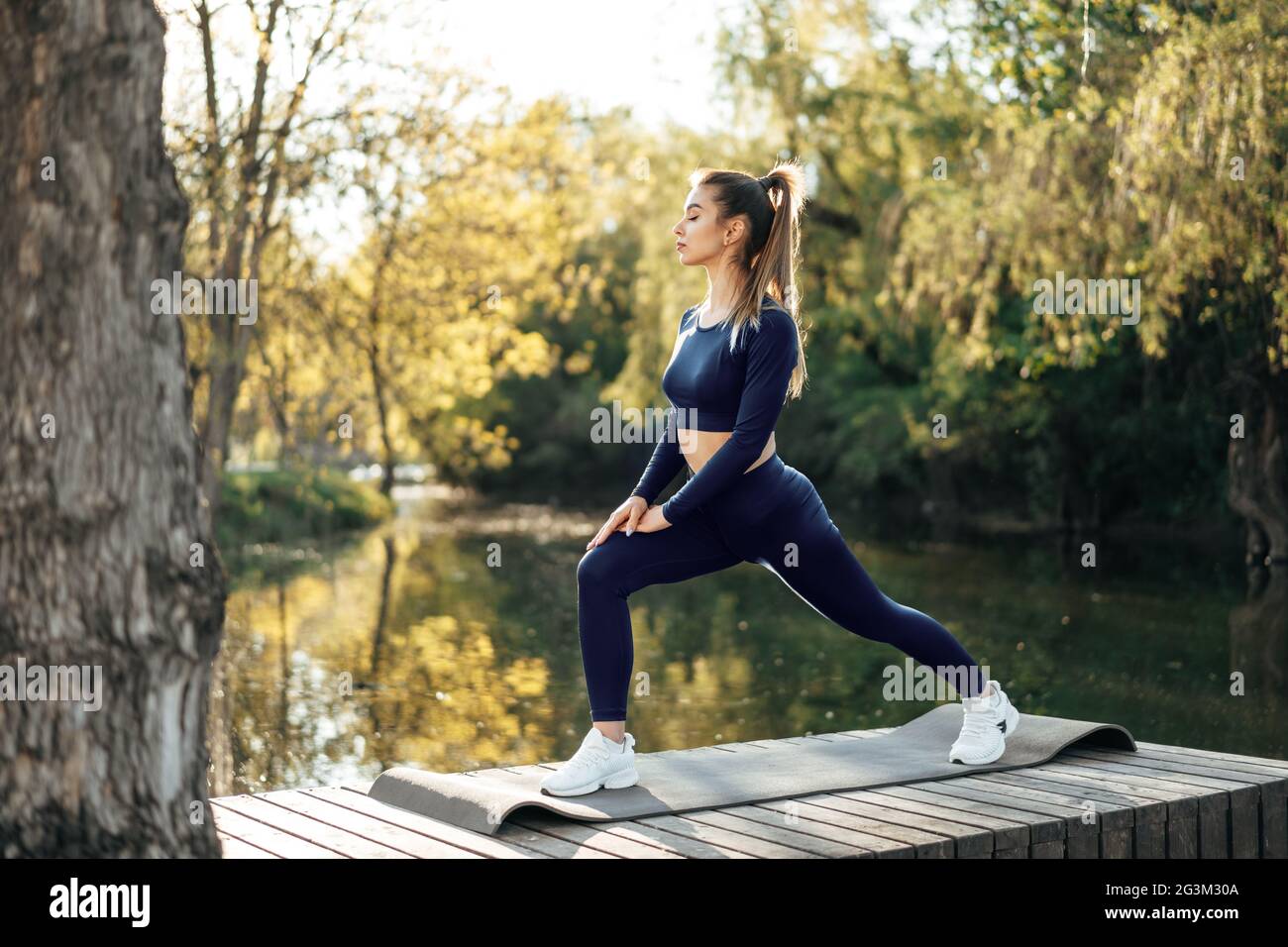 Fit young woman exercising on mat in the park Stock Photo - Alamy
