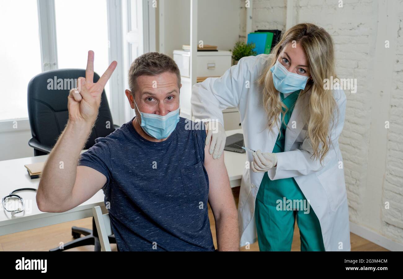 Female doctor or nurse vaccinating young man in clinic. Male Patient Getting Vaccinated Against Coronavirus Receiving covid Vaccine Intramuscular Inje Stock Photo