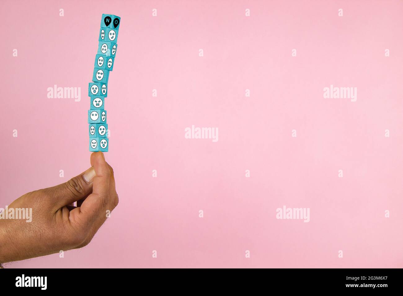hand holding a stack of wooden blocks in balance with shapes of a