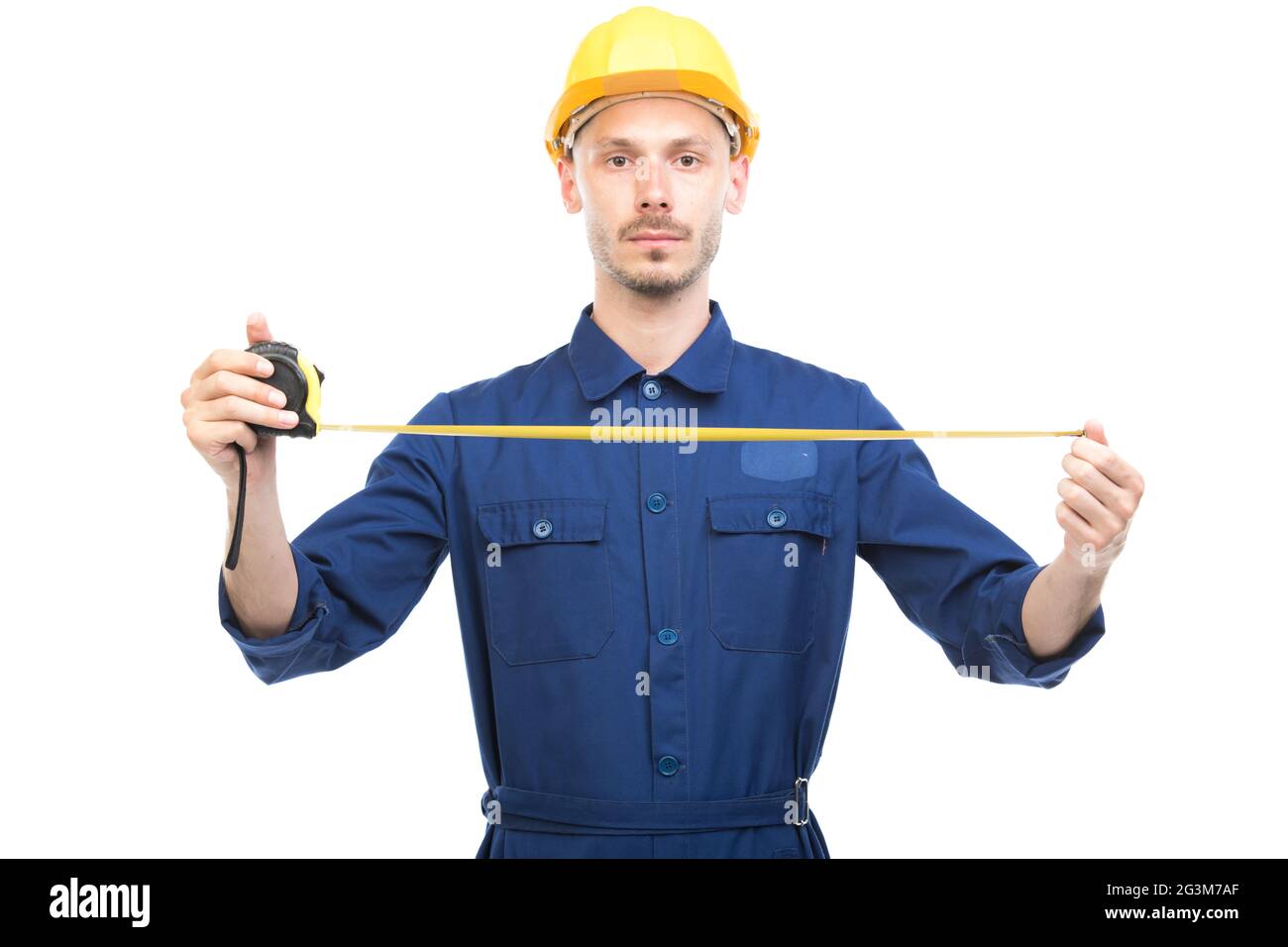 Horizontal portrait of successful handsome Caucasian construction engineer wearing uniform with hardhat measuring width or length of something Stock Photo