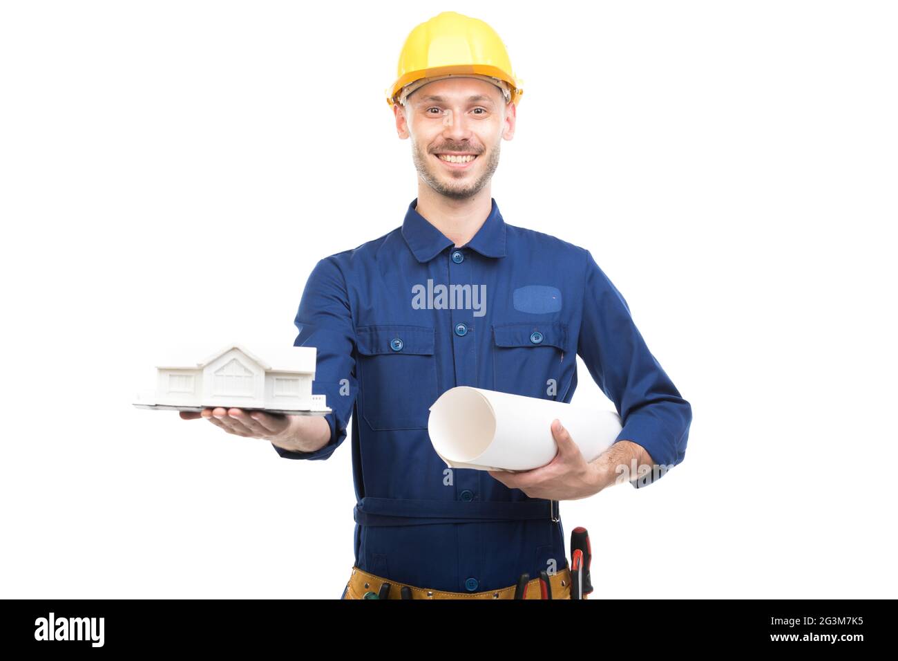 Horizontal medium portrait of modern handsome young adult Caucasian engineer wearing blue uniform holding construction plan and house model Stock Photo