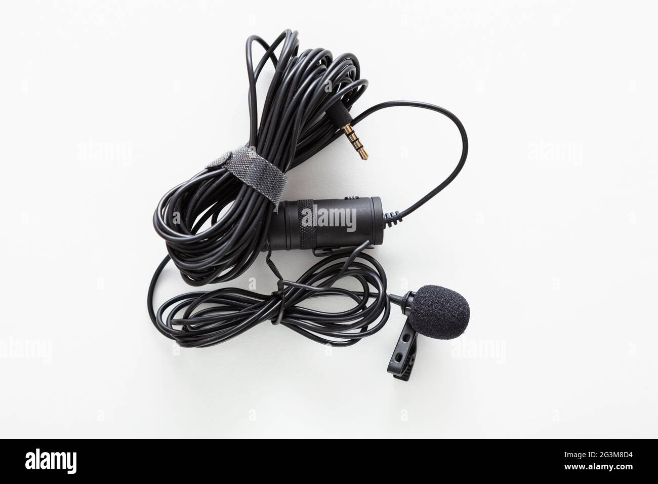 Black lapel microphone with clip and very long cable placed on a white background Stock Photo