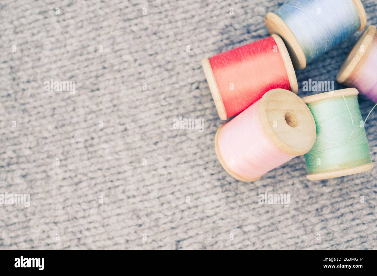 Colorful sewing threads on top of a grey fabric with free space for ...