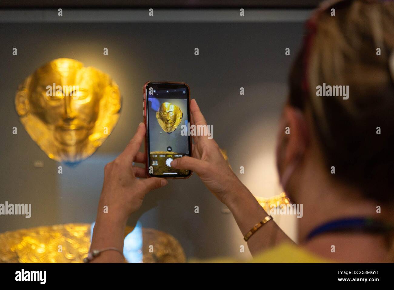 Athens, Greece. 7th June, 2021. A visiter takes pictures of exhibits at the National Archaeological Museum in Athens, Greece, June 7, 2021. The imposing golden mask of Agamemnon welcomes visitors at the National Archaeological Museum here, standing out among other finds from the royal cemetery of the ancient city of Mycenae on the Peloponnese peninsula dating back to the 16th century BC. TO GO WITH 'Interview: Ancient Greek golden death-masks of Mycenae still engulfed in mystery, says archaeologist' Credit: Marios Lolos/Xinhua/Alamy Live News Stock Photo