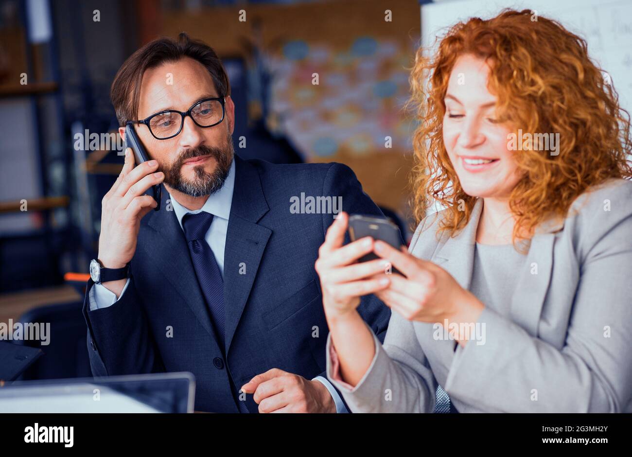 Businessman and businesswoman at working space communicating on phone. Stock Photo