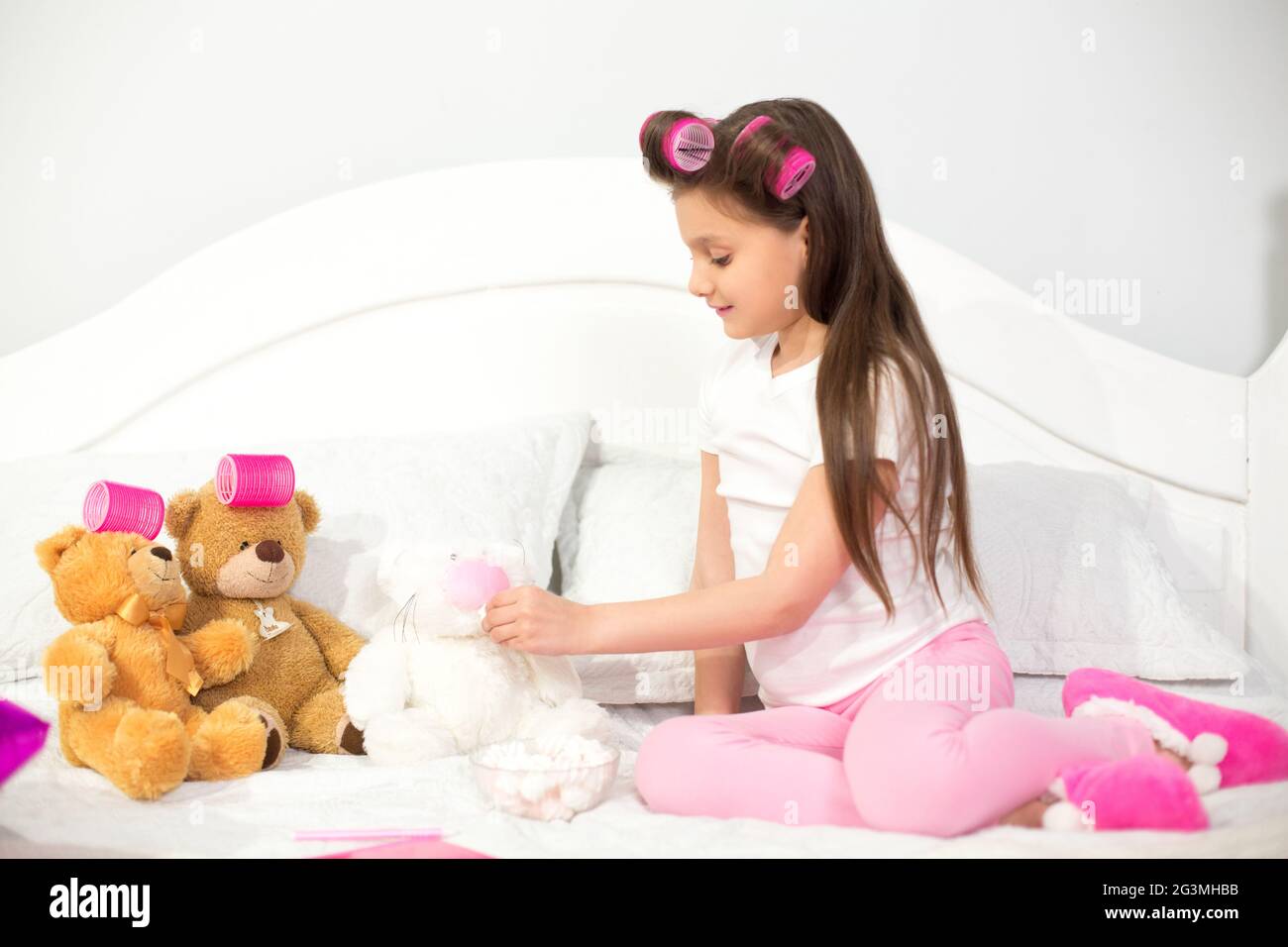 Cute girl playing with stuffed animals in bed Stock Photo - Alamy