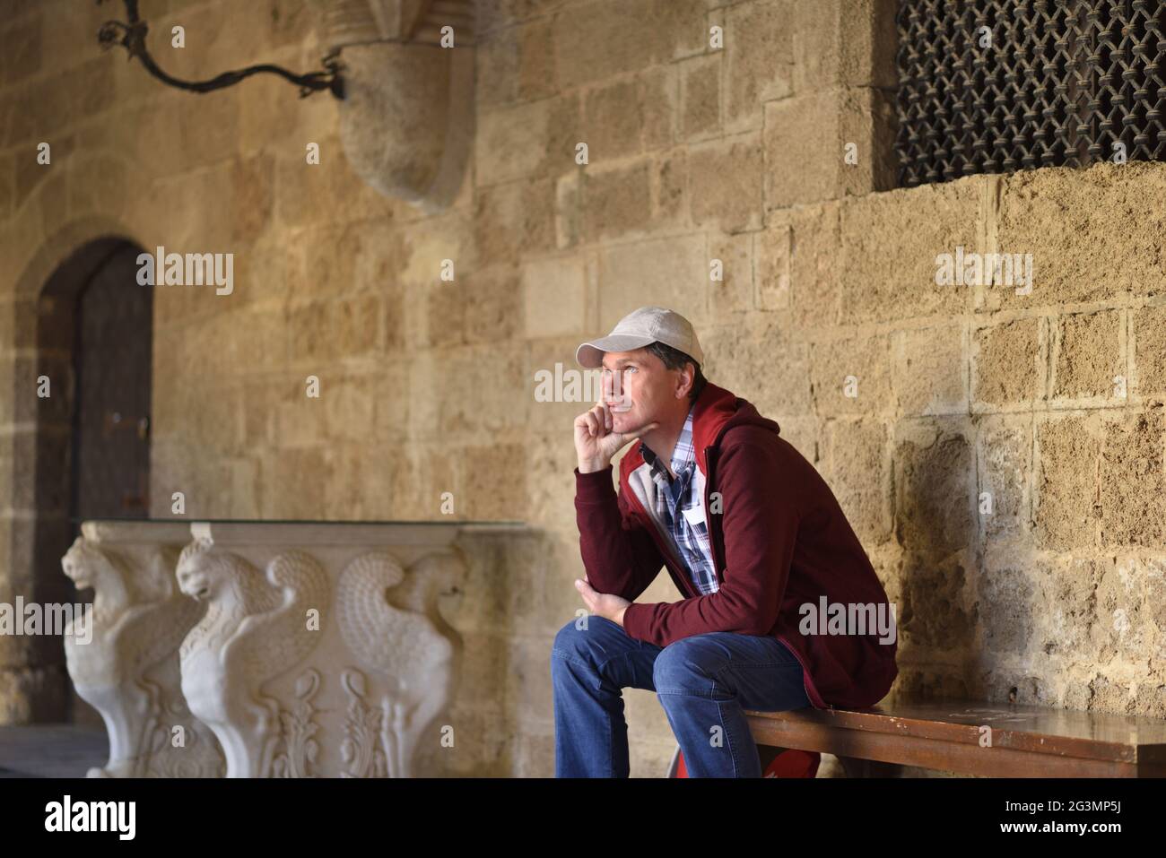 Tourist resting on a bench and looking away in the old city of Rhodes, Greece Stock Photo