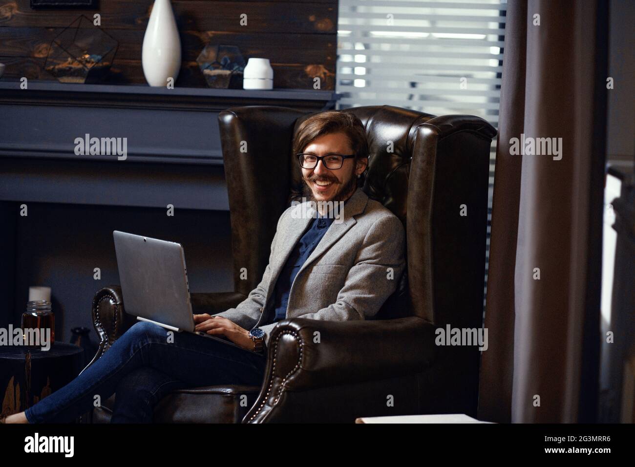 Smiling happy young man sitting in co-working office room Stock Photo