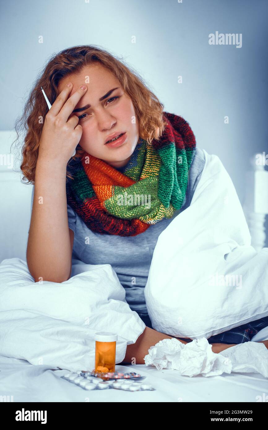 Sick blonde girl is scarf touches her head. In bed Stock Photo