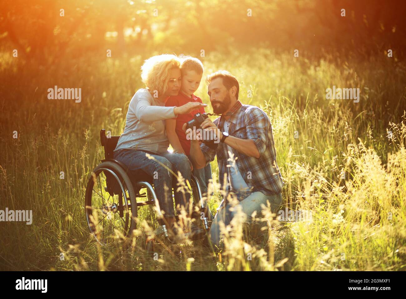 Photographer takes pictures of happy family where woman is in a wheelchair Stock Photo