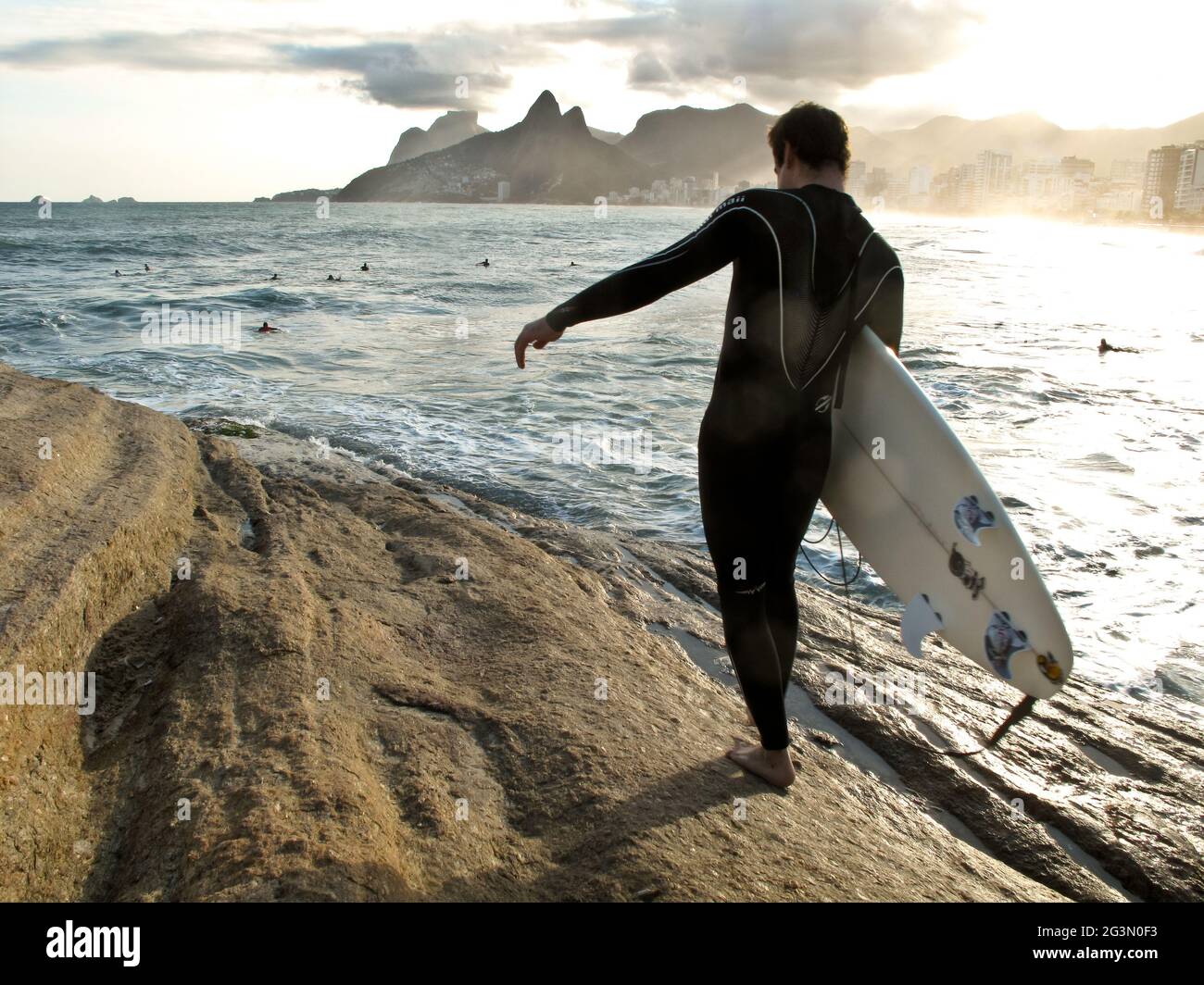 A surfer ready to jump into the water at Arpoador, the rock between Ipanema and Copacabana beaches, in Rio de Janeiro. Ipanema is in the background. Stock Photo