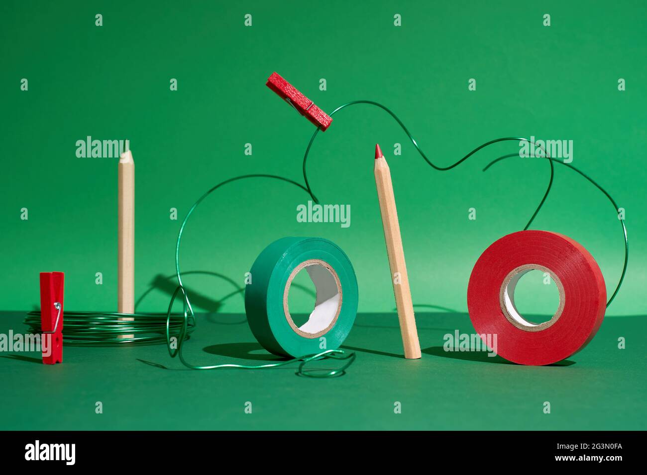 Creative art set pencils, red and green tape, pins, green wire on green back Stock Photo