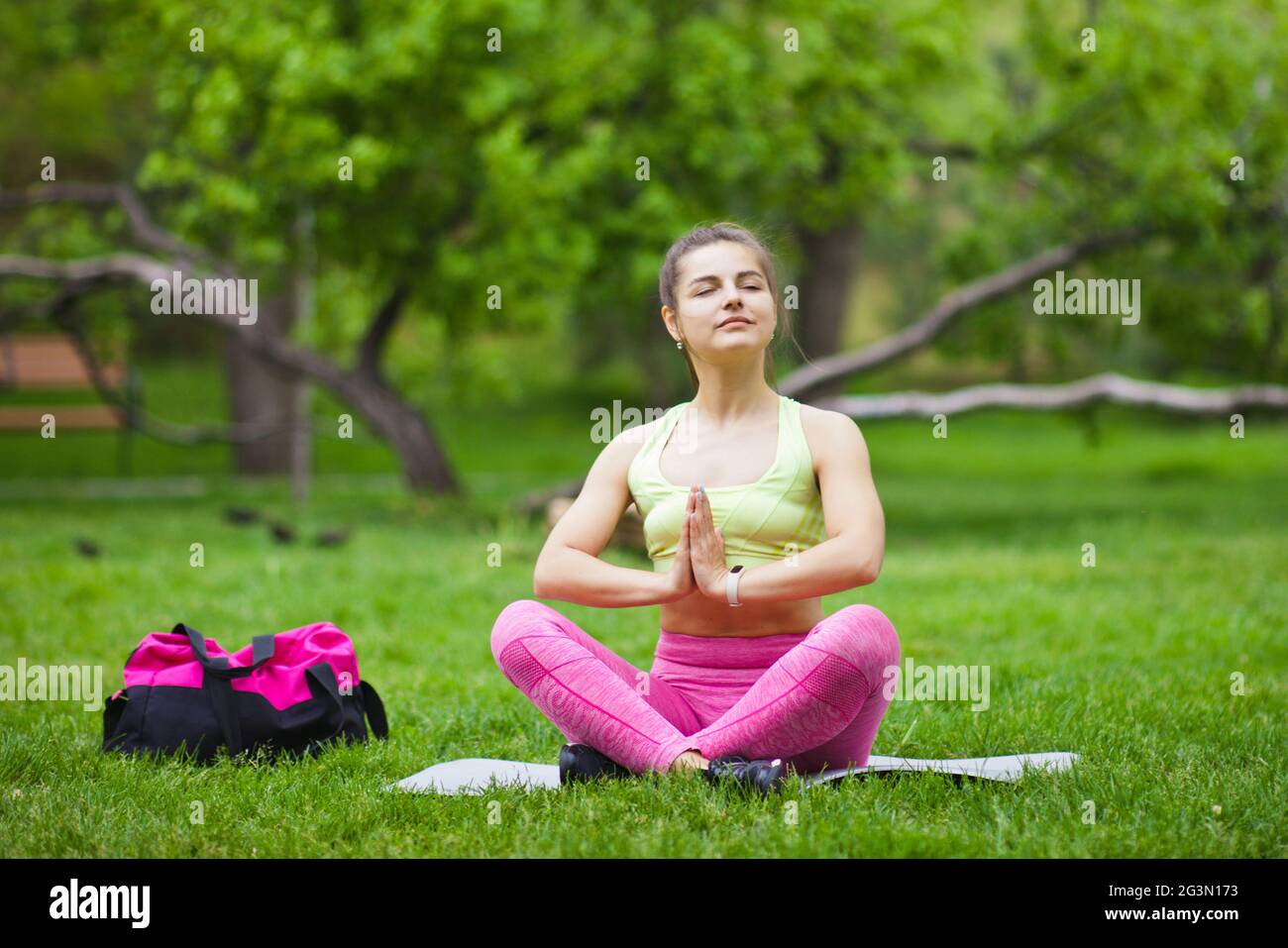 Sporty woman in yoga pose sitting on a mat in the park outdoors Stock ...