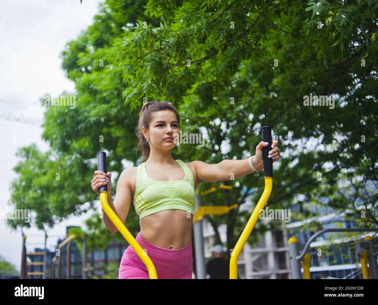Attractive athletic woman doing exercises on exercise machines on the sports ground outdoors Stock Photo