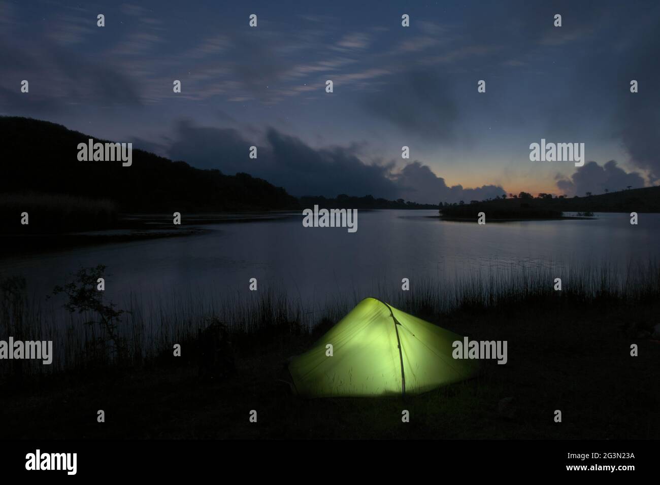 outdoor adventure in tent in the Sicily nature, wild camp by a lake at dusk in Nebrodi mountains Stock Photo
