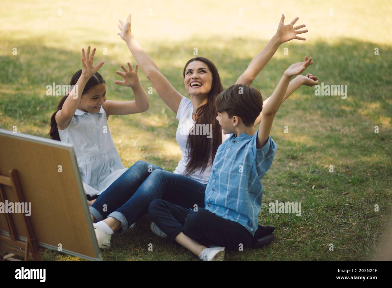 Children and teacher posing with raised hands Stock Photo - Alamy