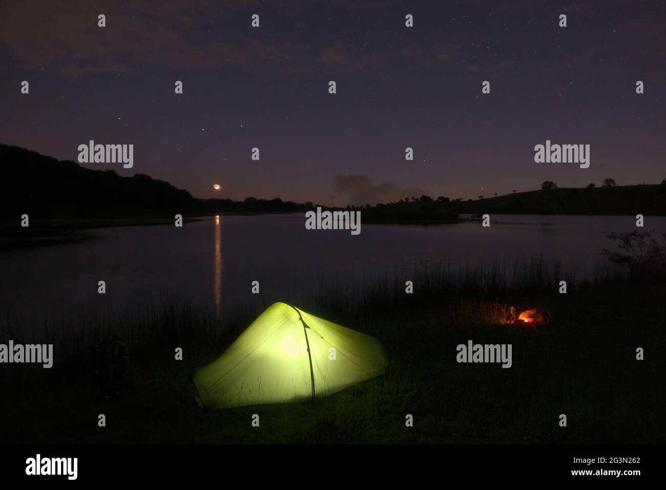 outdoor adventure in tent in the Sicily nature, moon set on wild camp by a lake in Nebrodi mountains Stock Photo