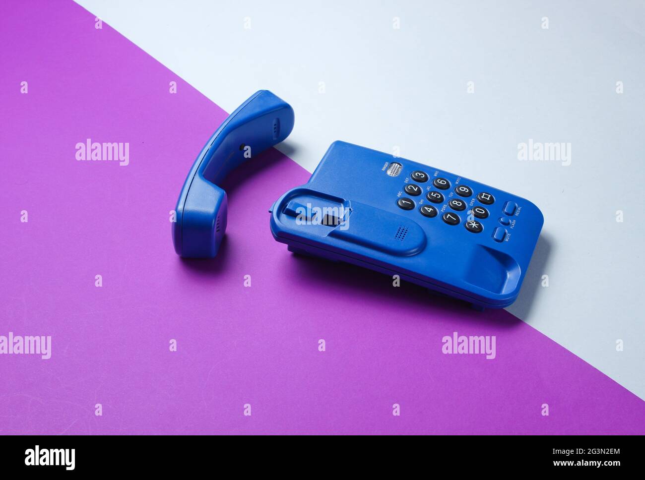 Wireless office phone with handset on purple gray background Stock