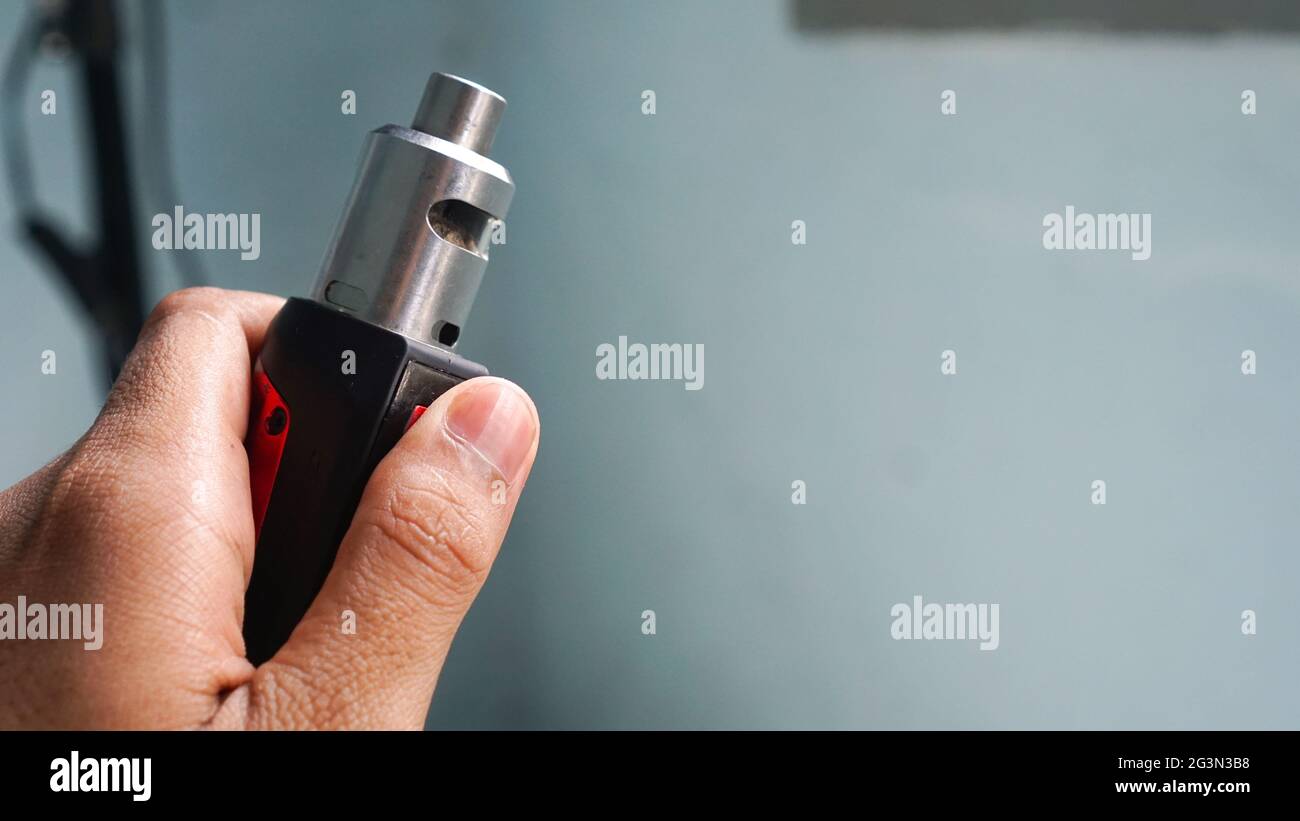 A man's hand is holding a vape or e-cigarette Stock Photo