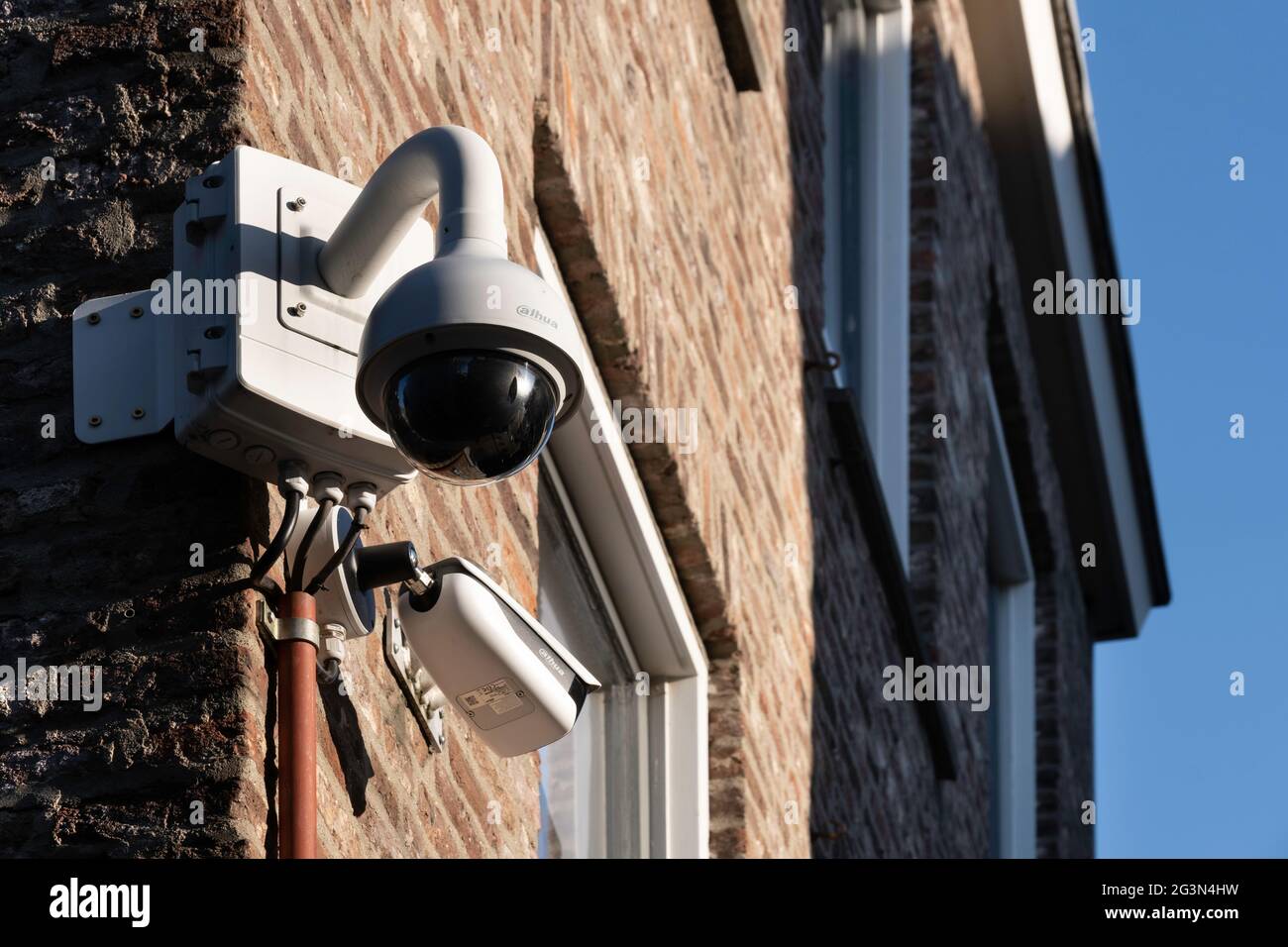 Two different types of surveillance or security CCTV cameras on a brick  wall of a shop in the center of Maastricht, the Netherlands. Blue sky Stock  Photo - Alamy