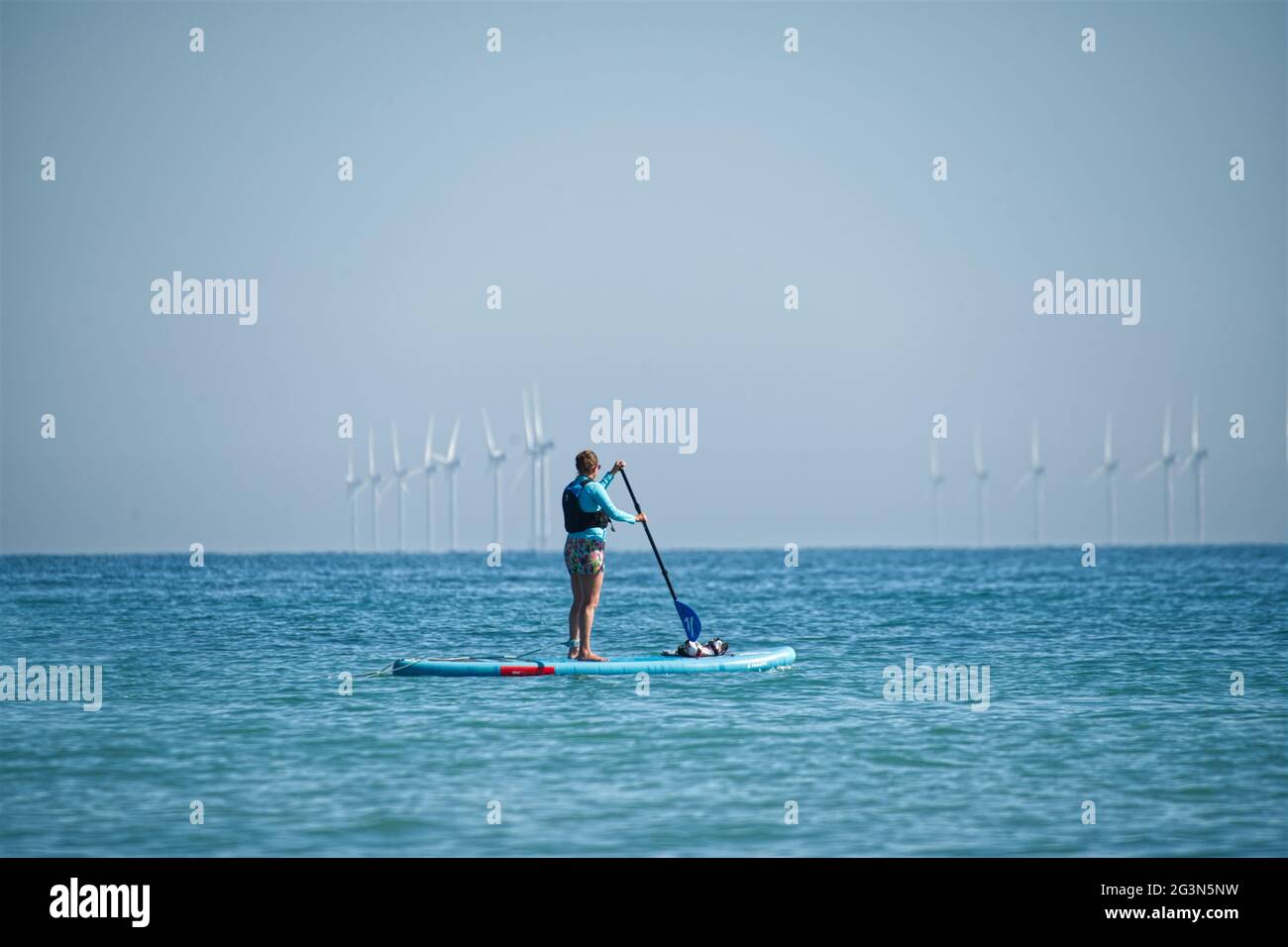 Paddle board by wind turbines Stock Photo Alamy