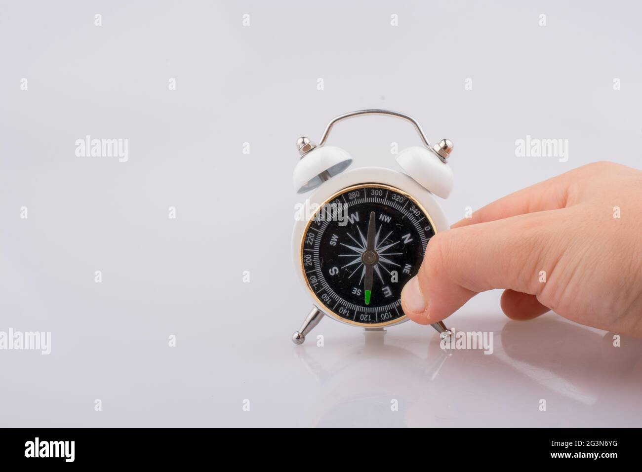 Child holding a compass on an alarm clock Stock Photo
