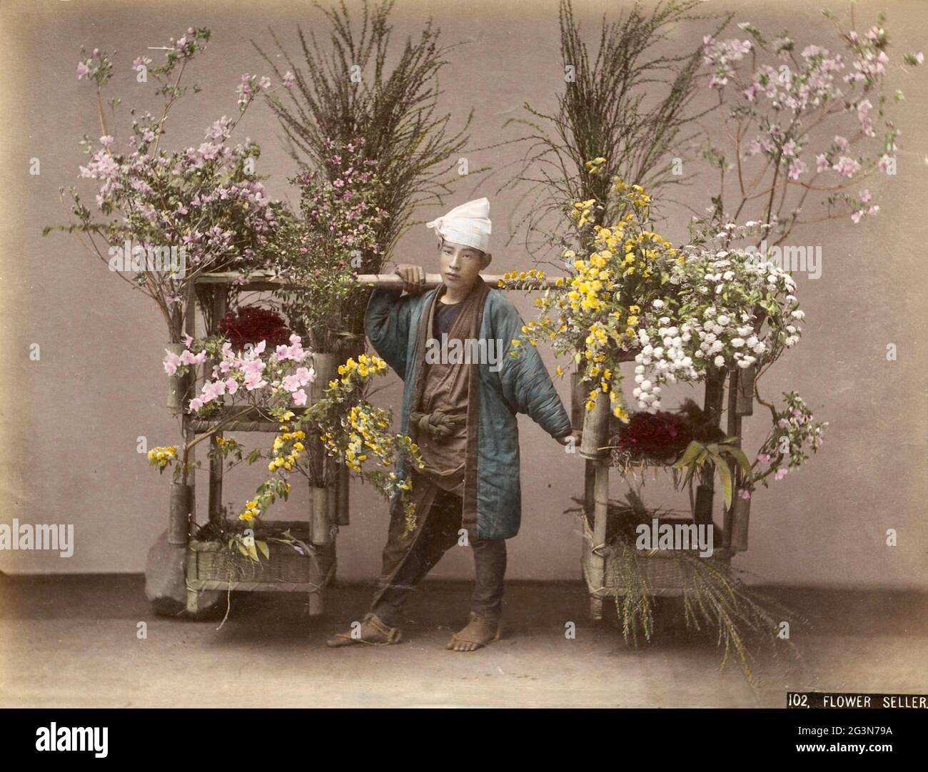 Vintage Kusakabe Kimbei photograph from Old Japan. A flower seller with his colourful array of blooms. Stock Photo