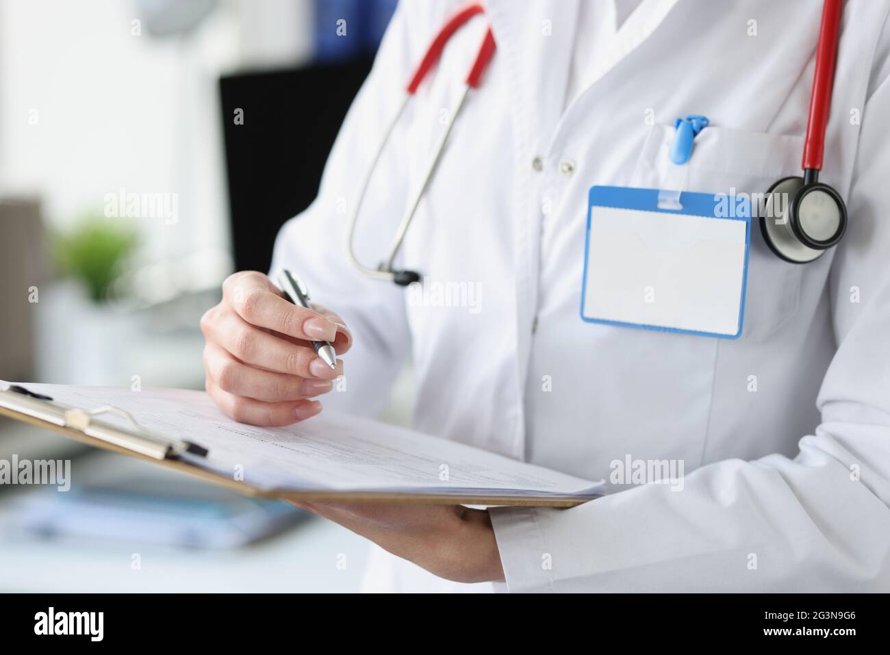 Female doctor holding clipboard with documents and ballpoint pen in her hands closeup Stock Photo