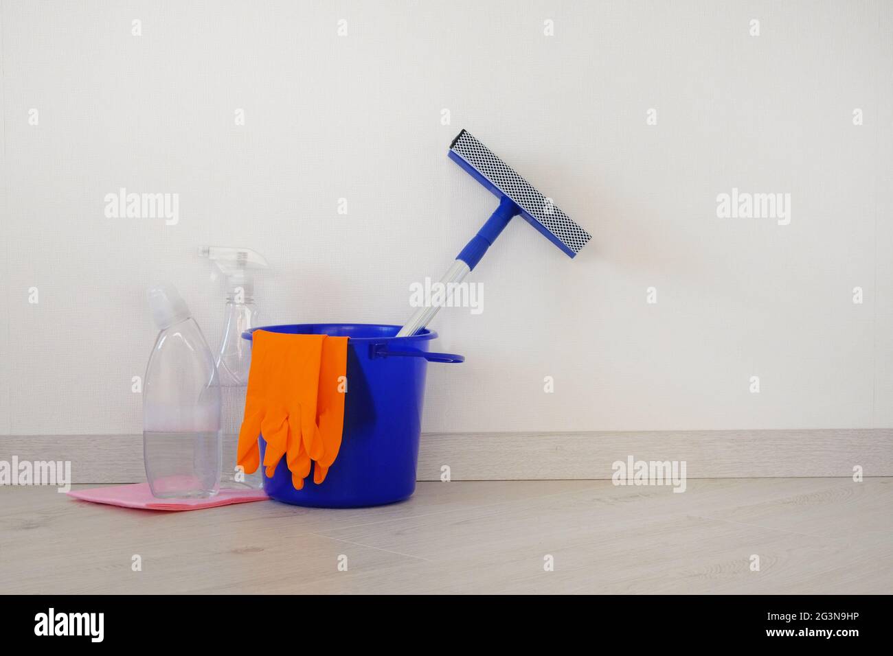 Housework and housekeeping concept. Bucket with cleaning agents, rubber protective glove and blue mop at home. Stock Photo