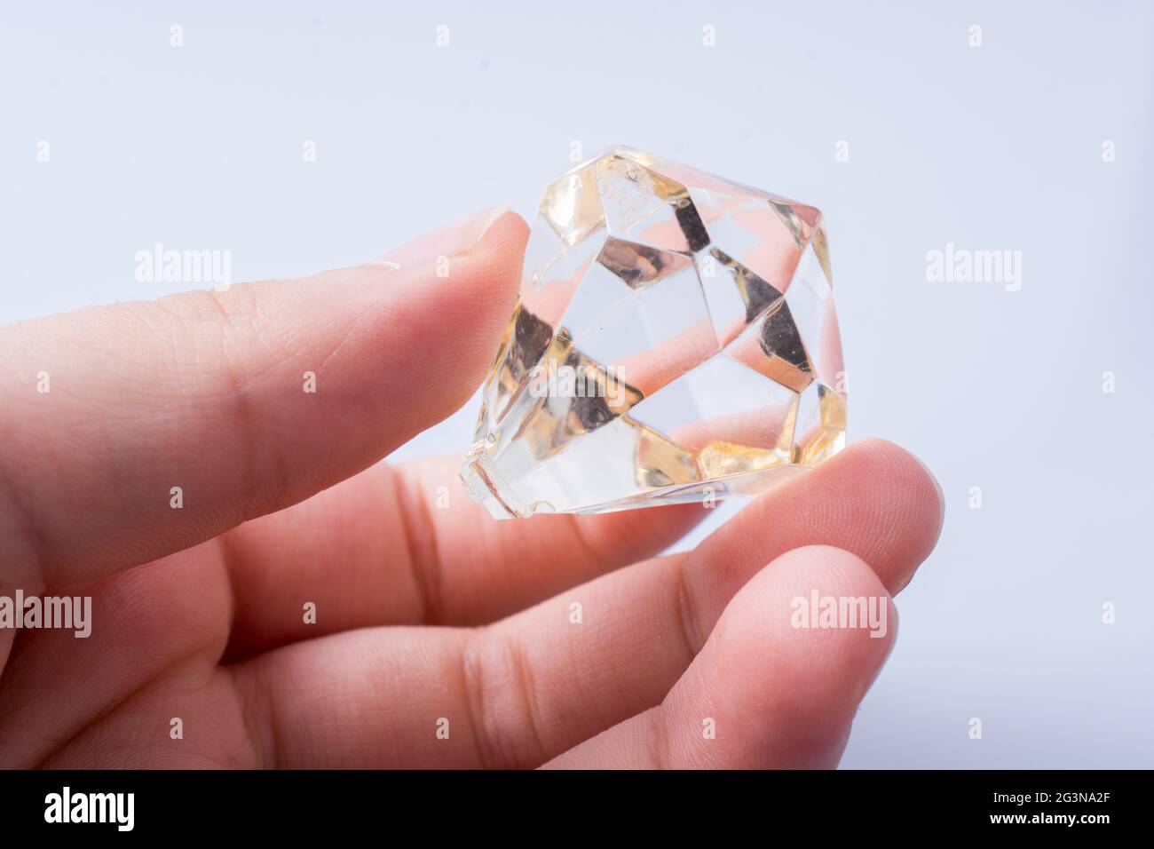 Hand holding a transparent diamond on white background Stock Photo